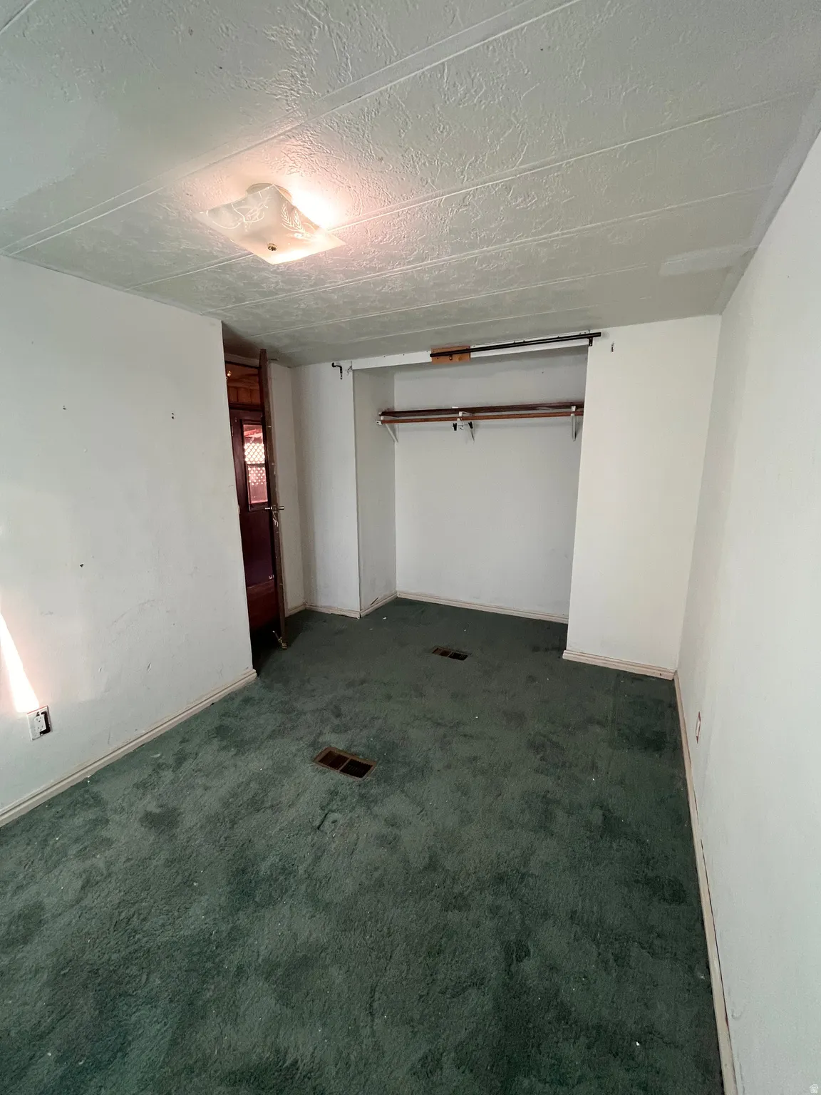 Below grade area with dark colored carpet and a textured ceiling