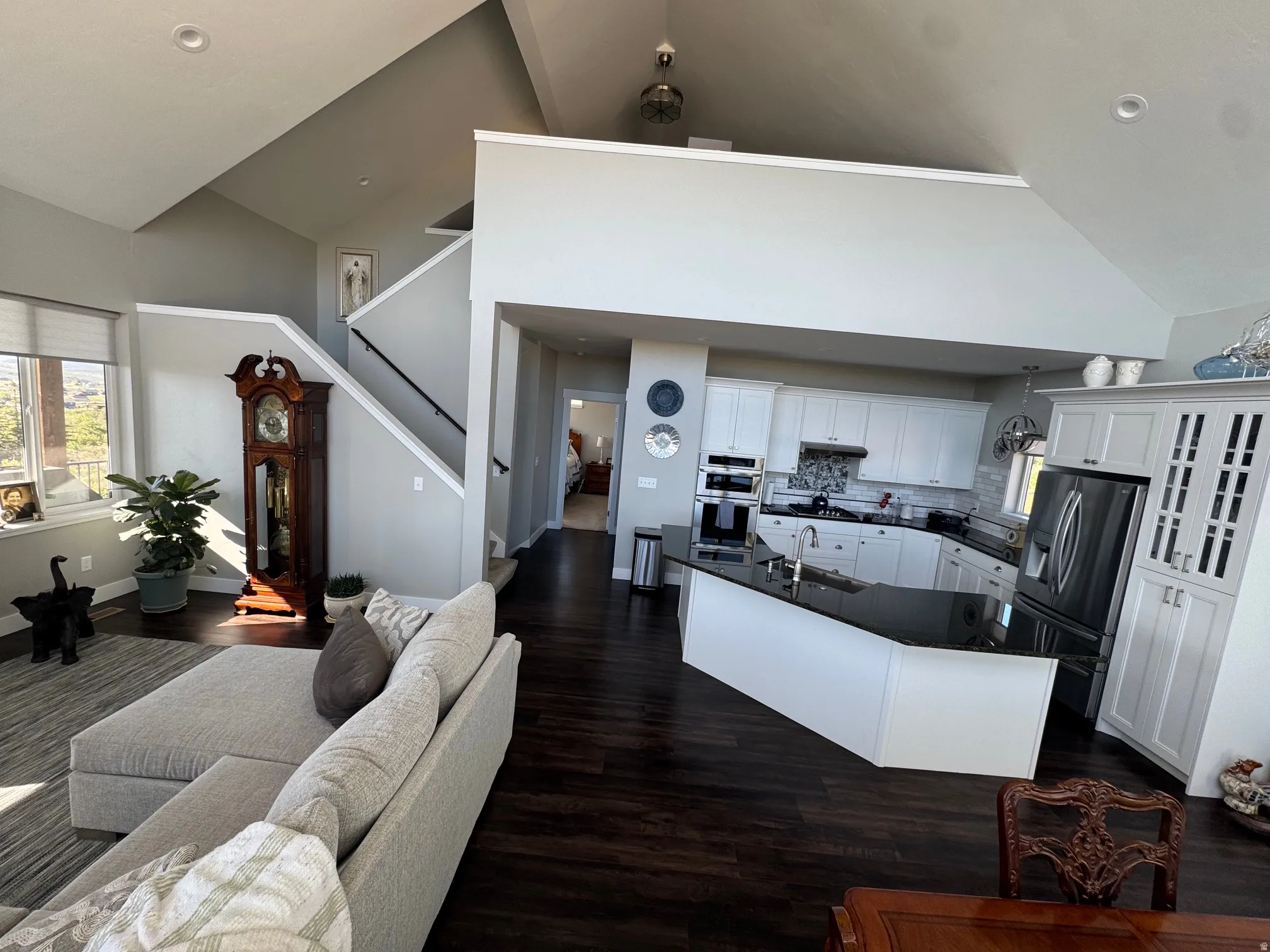 Open-concept living area featuring high vaulted ceilings, recessed lighting, and dark wood-finish flooring