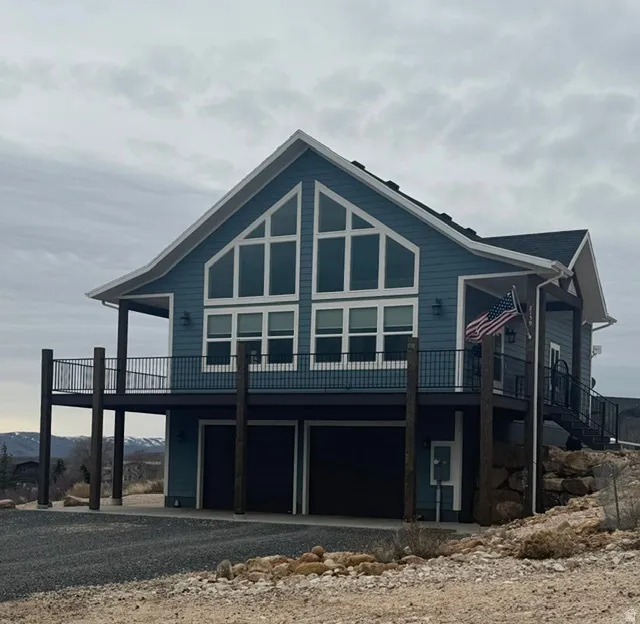 View of front of home featuring an attached garage, a wooden deck, and driveway