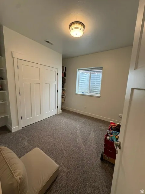 Bedroom with a closet and dark colored carpet