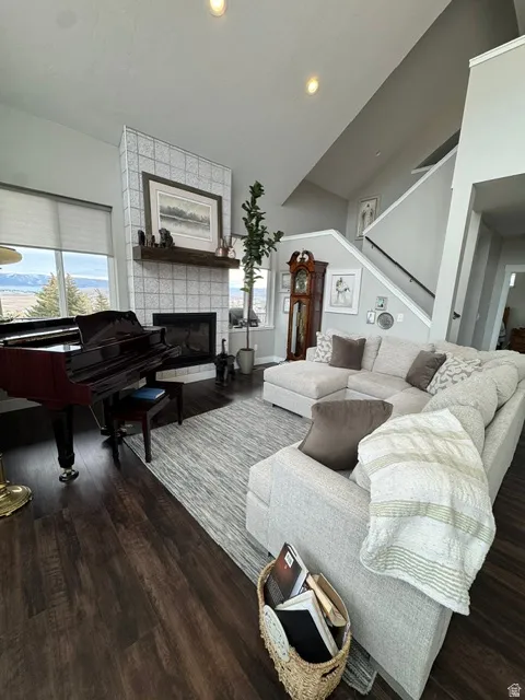 Living area with healthy amount of natural light, wood finished floors, a tile fireplace, recessed lighting, and vaulted ceiling
