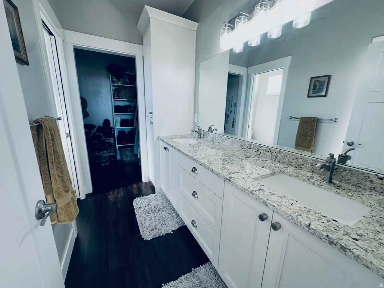 Full bath featuring double vanity and dark wood finished floors
