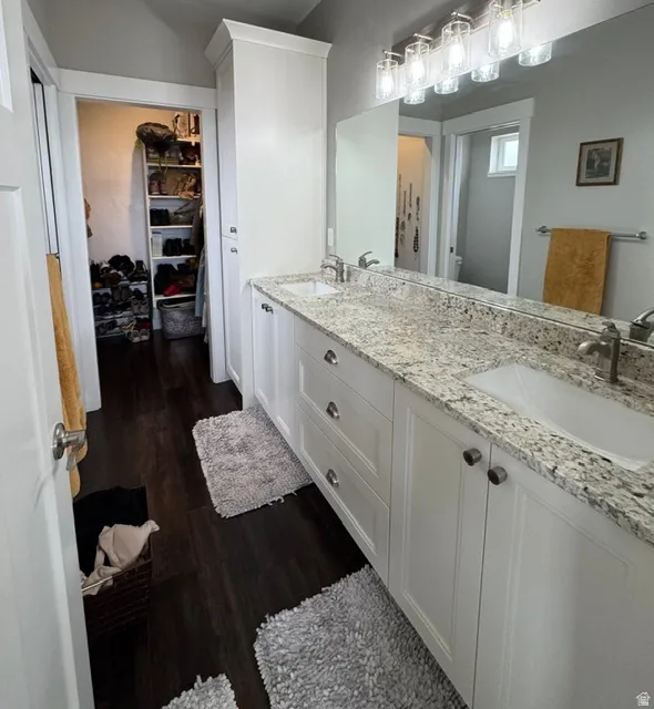 Full bathroom with double vanity and dark wood finished floors