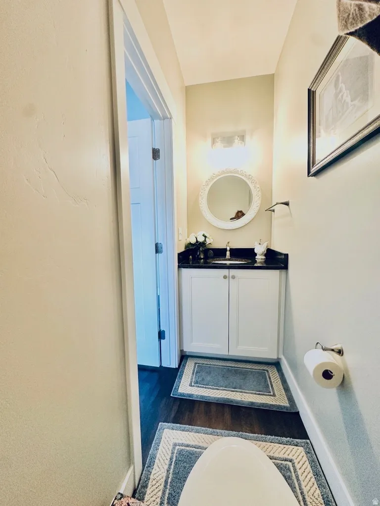 Half bathroom with vanity and dark wood-type flooring