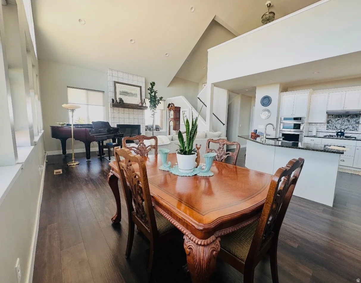 Dining space featuring dark wood finished floors, a fireplace, and lofted ceiling