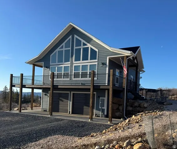 View of front of home featuring an attached garage, a wooden deck, and gravel driveway