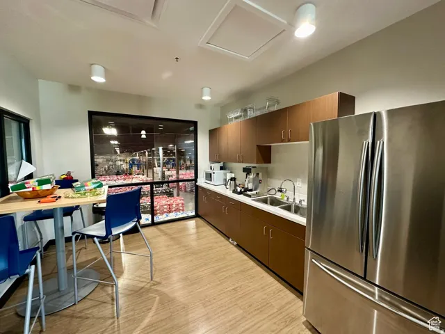 Kitchen featuring freestanding refrigerator, light countertops, light wood finished floors, white microwave, and dark wood finish cabinetry