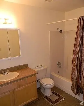 Bathroom with vanity, shower / bath combo, and dark tile patterned floors