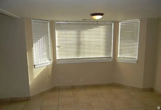Empty room with baseboards and light tile patterned floors