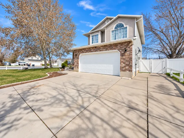 Two-story residence featuring a brick and siding exterior, an attached two-car garage, a concrete driveway, and a white privacy fence