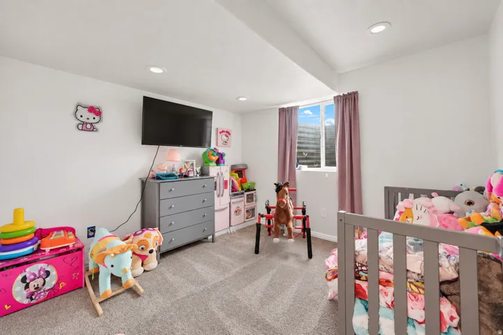 Recessed ceiling lighting, wall-mounted television, and a window with blinds