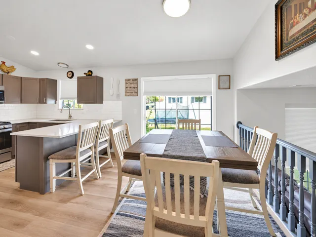 Open-concept kitchen with wood-finish flooring, white subway tile backsplash, and a large island with seating