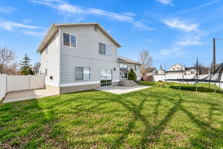 Two-story residence with siding exterior, concrete patio, and a privacy fence enclosing the yard
