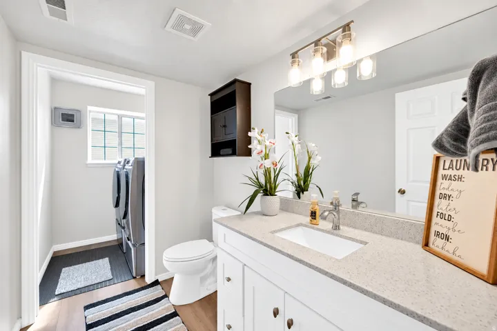 Bathroom featuring a single vanity with stone-finish countertop, undermount sink, and wood-finish flooring
