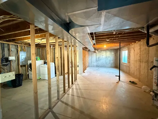 Basement featuring electric panel and washing machine and clothes dryer