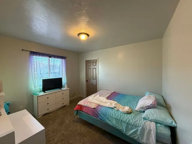 Bedroom with dark carpet and a textured ceiling