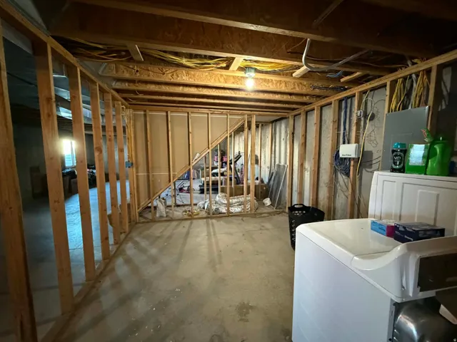 Unfinished below grade area featuring washer / dryer and electric panel