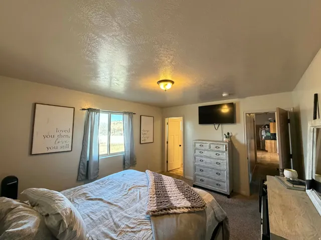 Bedroom with dark colored carpet and a textured ceiling