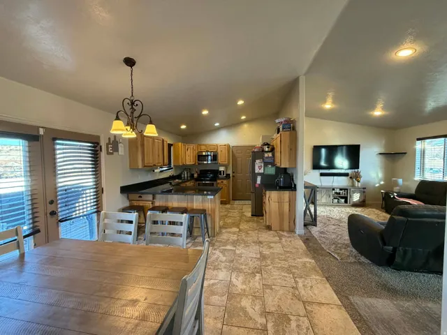 Kitchen featuring dark countertops, a peninsula, open floor plan, vaulted ceiling, and suspended lighting