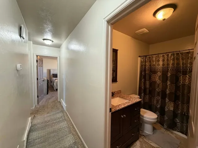 Corridor with light carpet and a textured ceiling