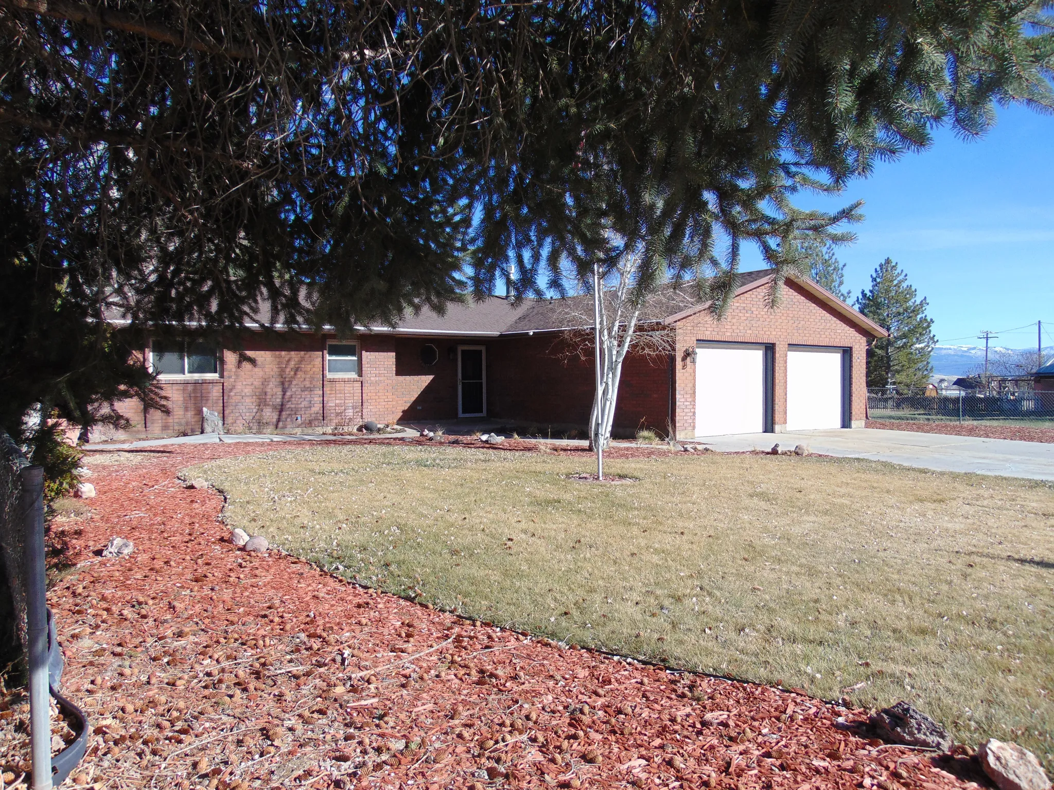 Ranch-style home featuring brick siding, an attached garage, driveway, and a front lawn