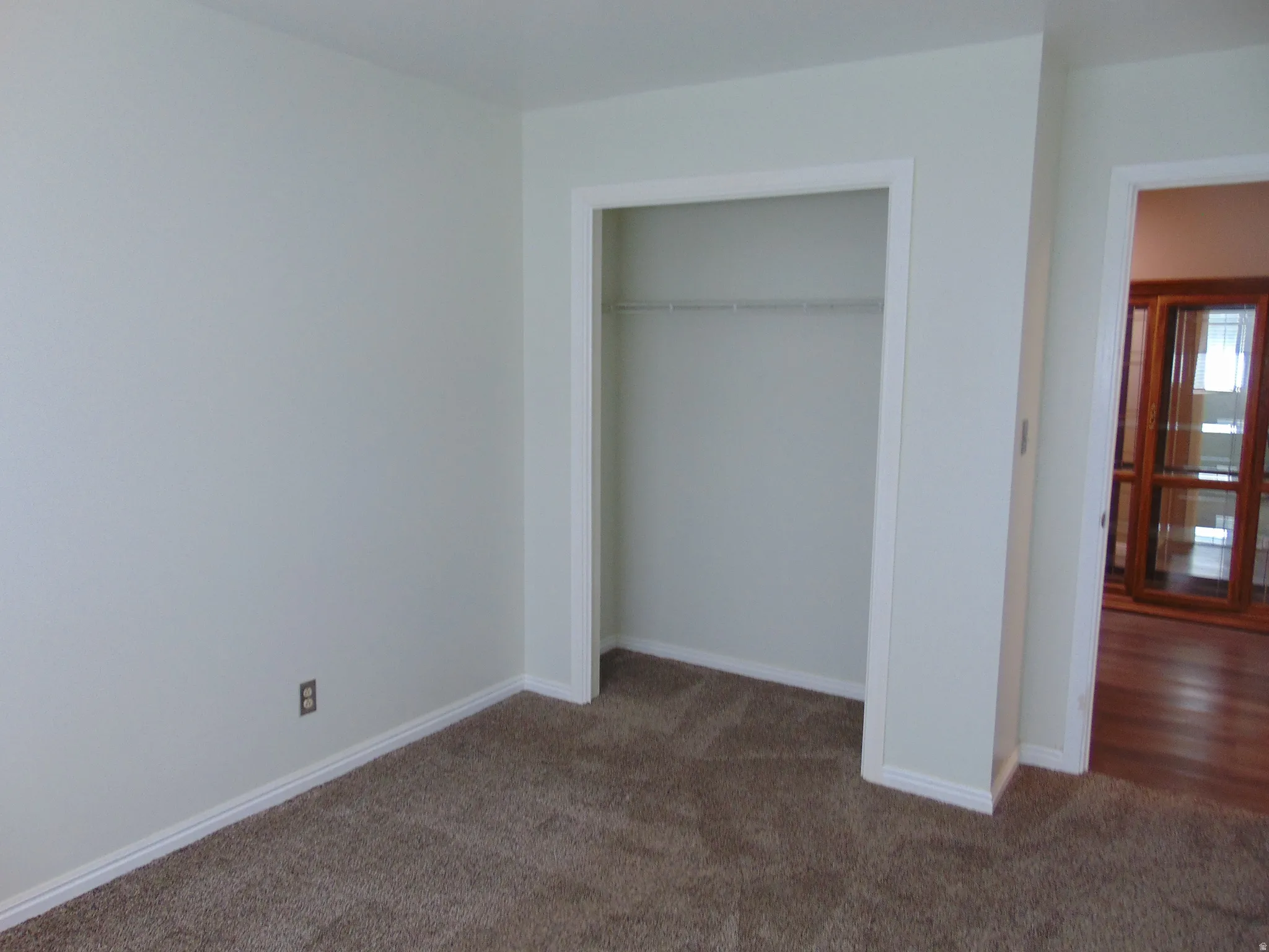 Unfurnished bedroom featuring dark carpet and a closet