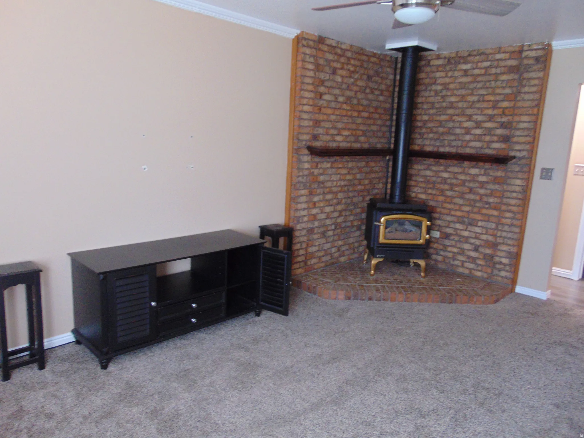 Living room with crown molding, a gas stove, carpet floors, and ceiling fan