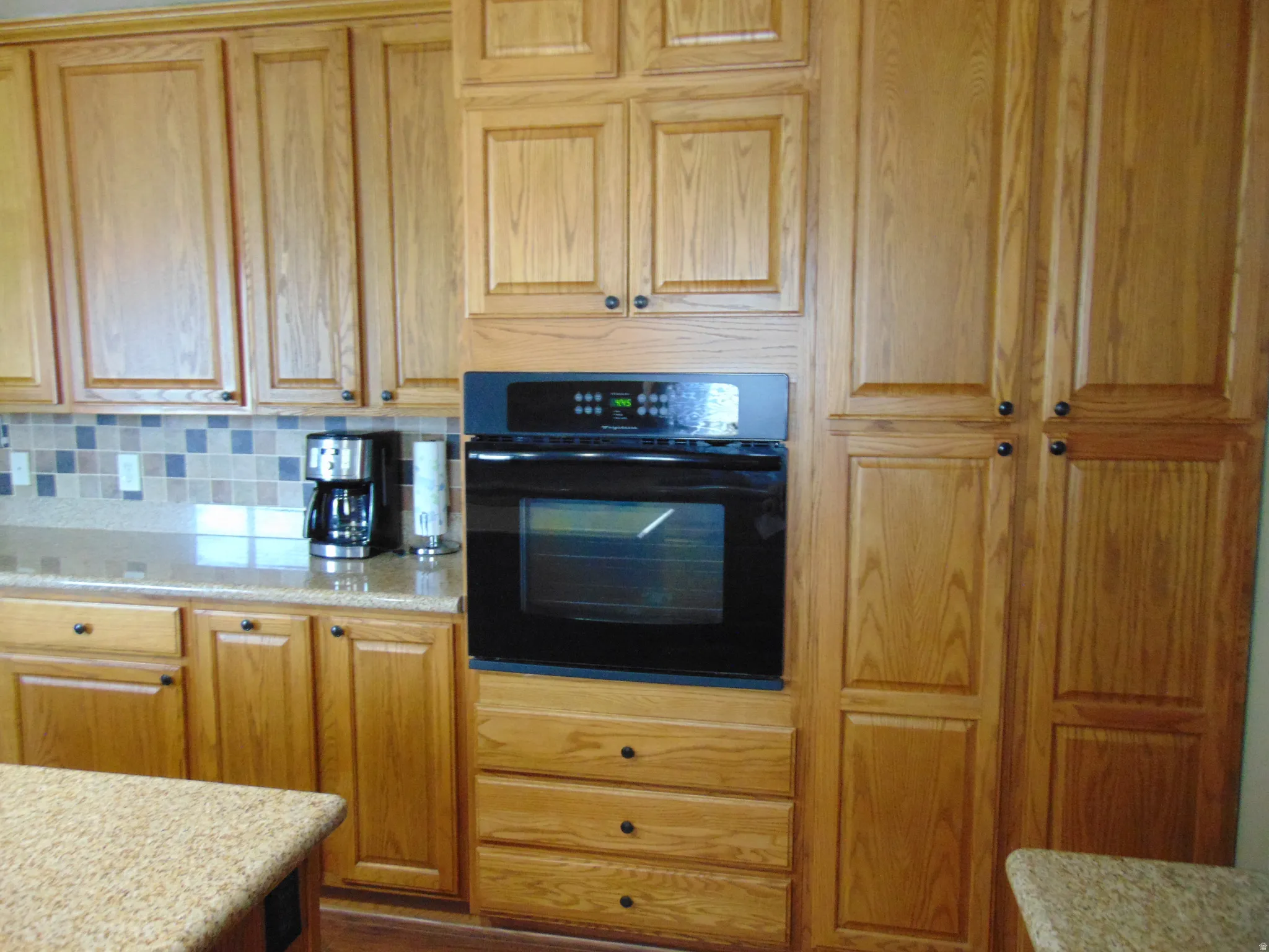 Kitchen featuring oven, decorative backsplash, and light stone counters