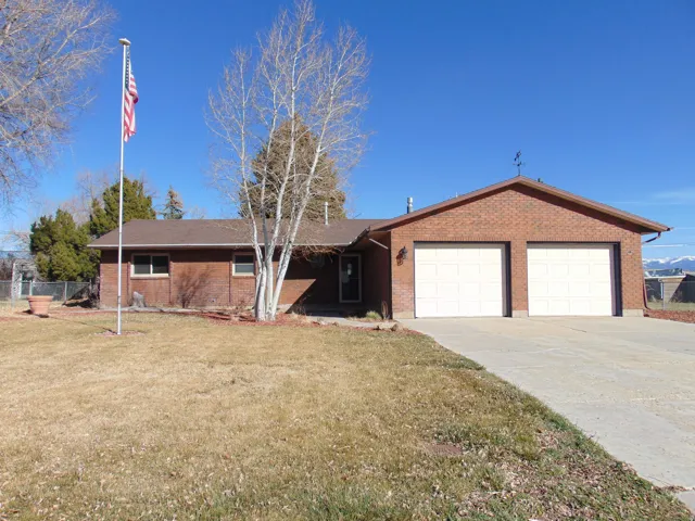 Ranch-style house featuring brick siding, a front lawn, driveway, and a garage