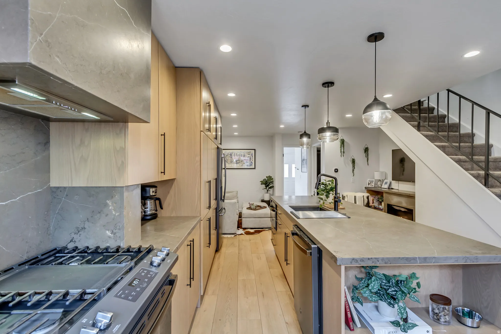 Kitchen with light wood finish cabinets, stainless steel appliances, a spacious island, light countertops, and light wood-style flooring