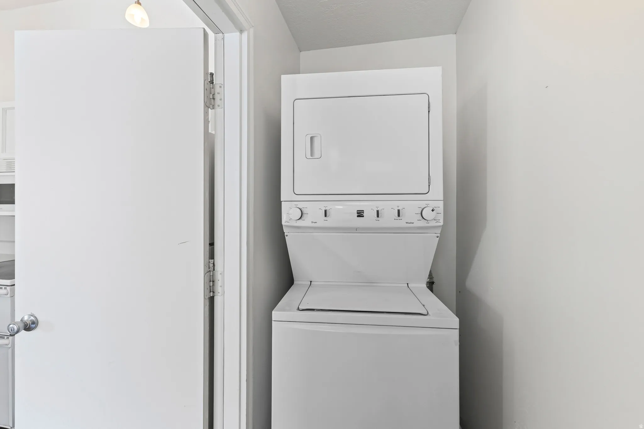 Laundry area featuring stacked washer / dryer and a textured ceiling
