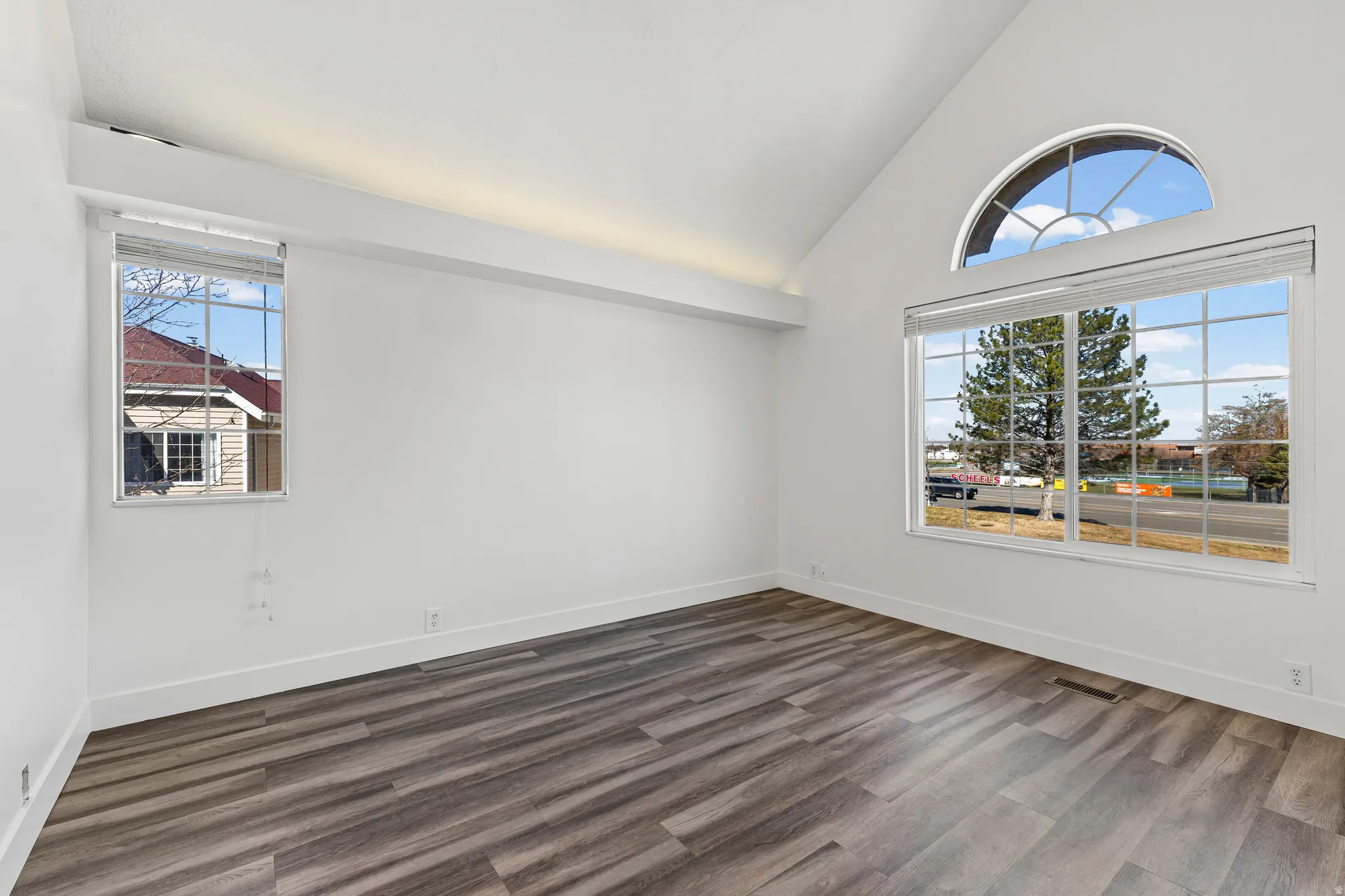 Spare room featuring vaulted ceiling and dark wood finished floors