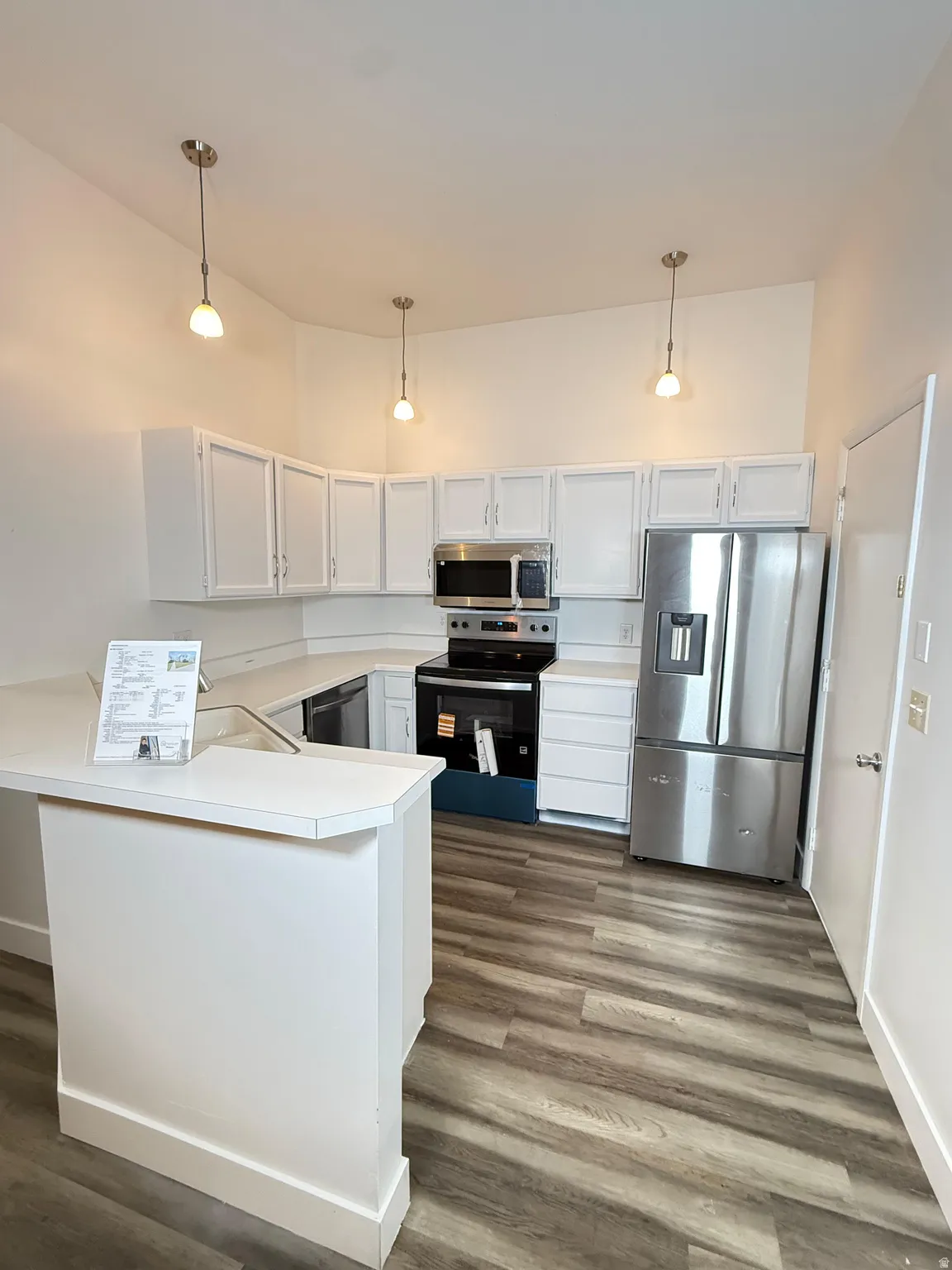 Kitchen featuring stainless steel appliances, light countertops, a peninsula, and white cabinets