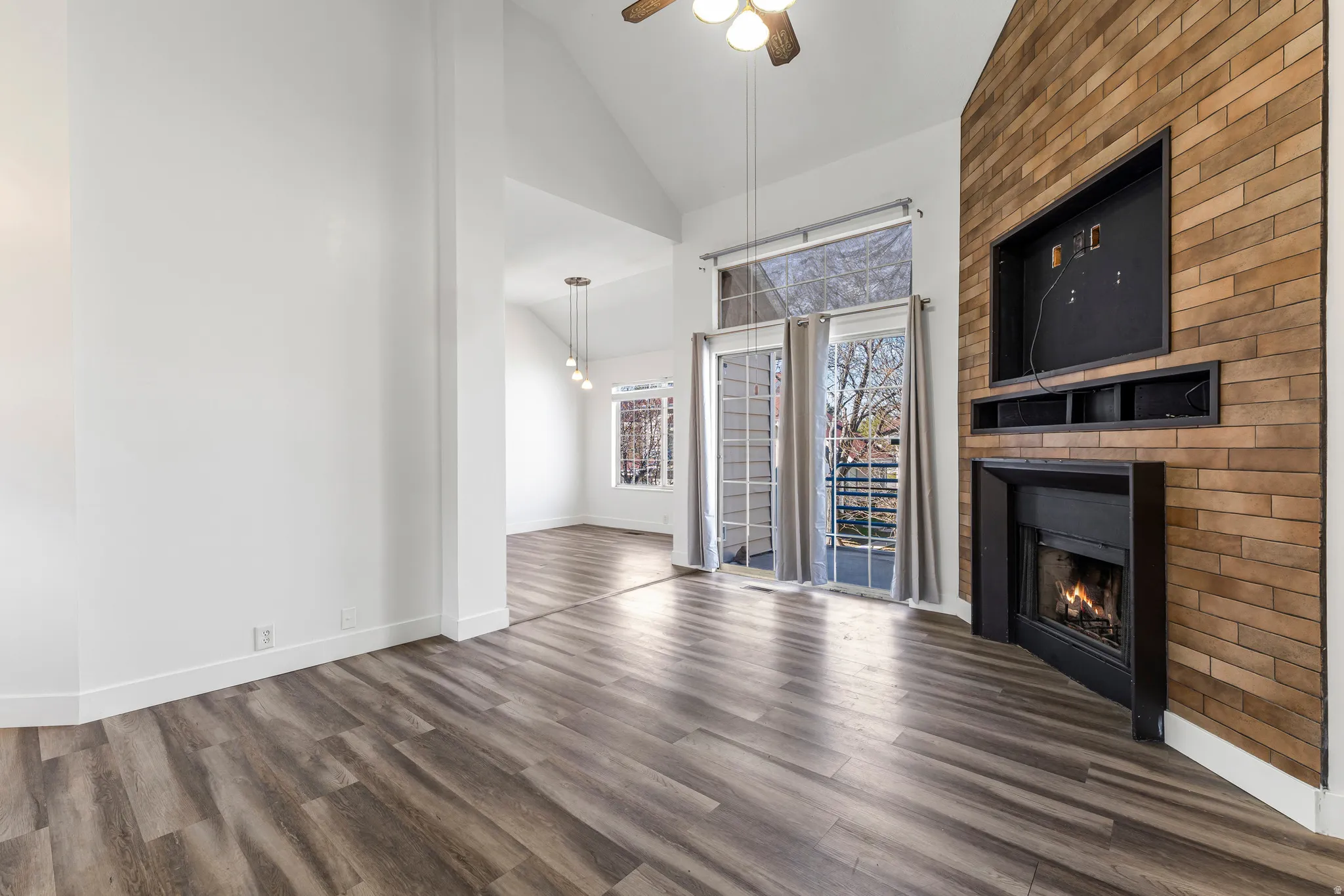 Unfurnished living room with lofted ceiling, dark wood-style flooring, a fireplace, and ceiling fan