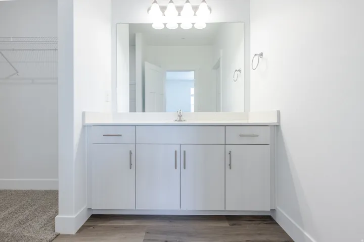 White vanity cabinet with integrated sink, chrome faucet, and expansive mirror