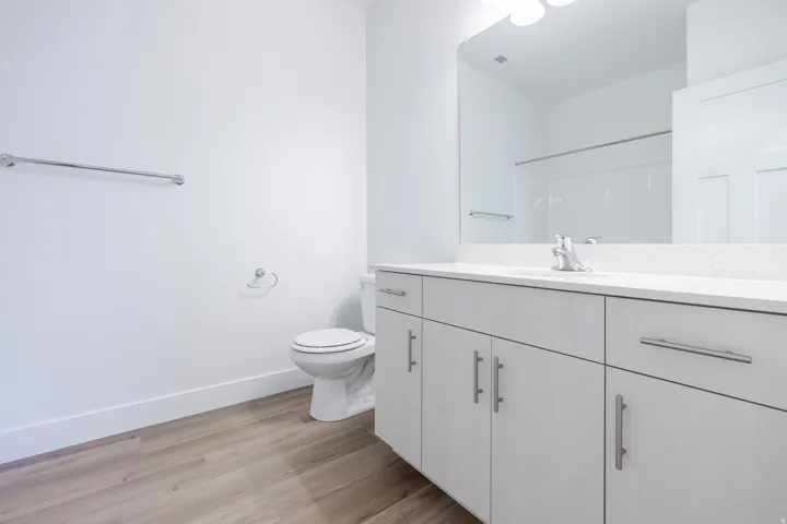 White vanity with a light countertop, integrated sink, and brushed nickel fixtures