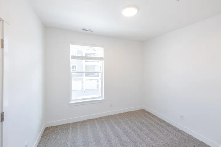 Recessed lighting, light gray carpet, white walls, white trim, and a window with blinds