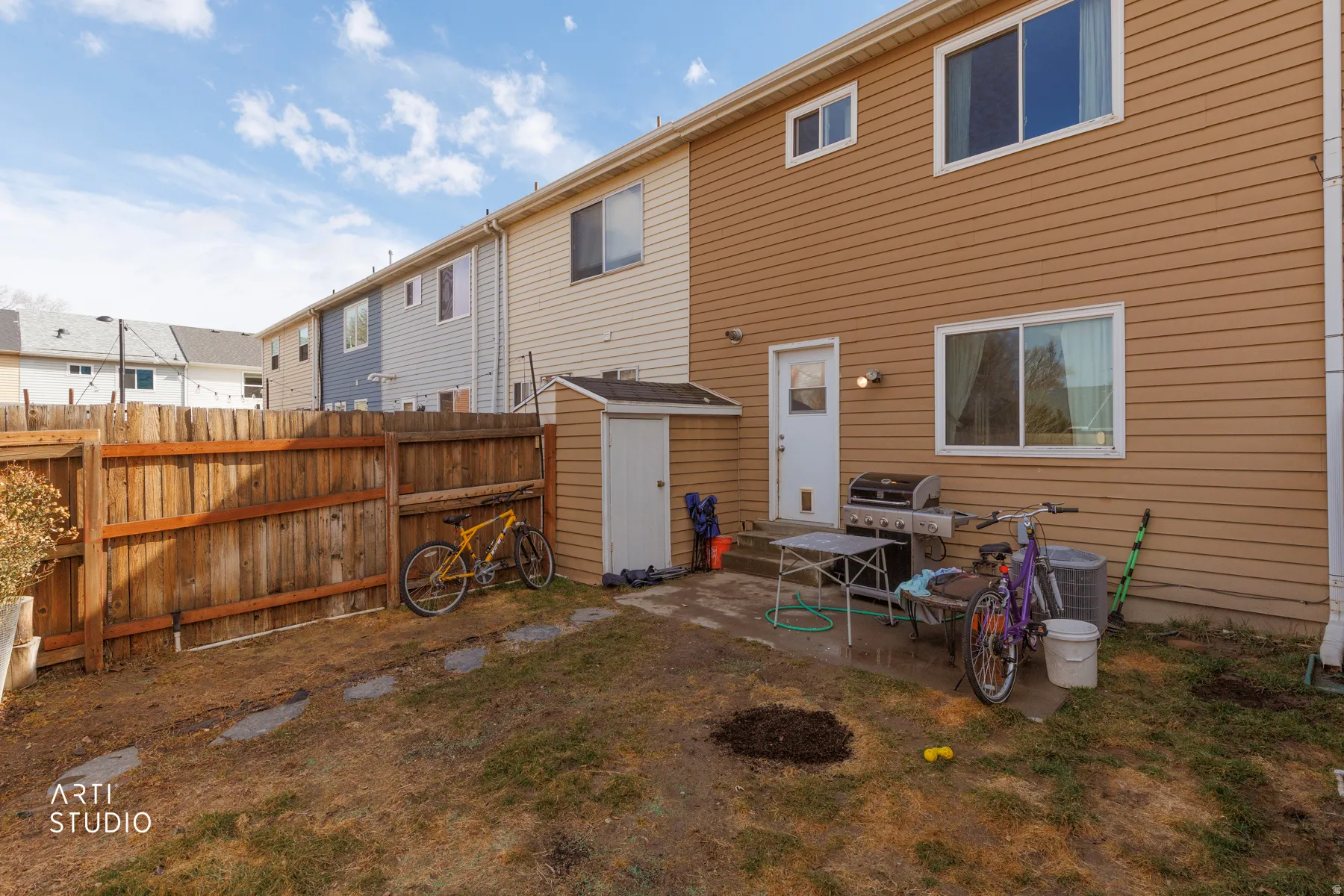 Rear view of property with a storage unit, a fenced backyard, and a patio