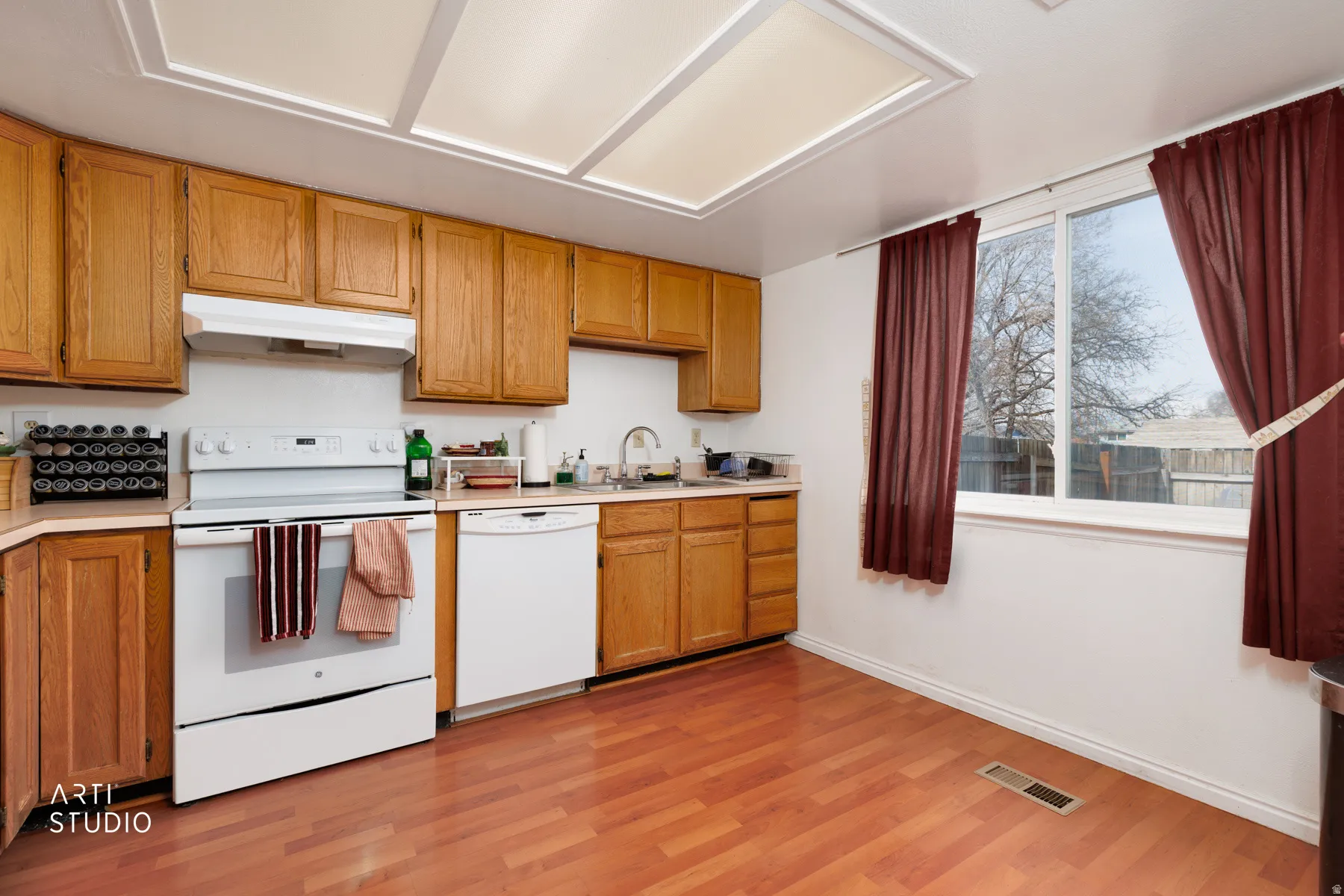 Kitchen featuring white appliances, light countertops, light wood-type flooring, and wood finish cabinetry