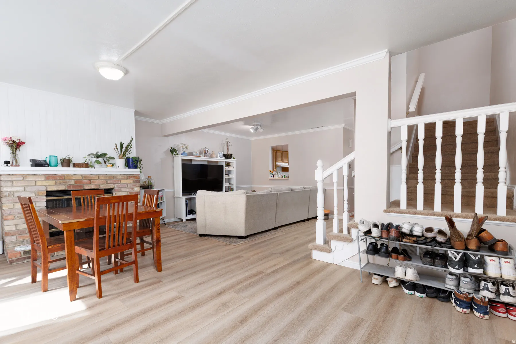 Dining area featuring light wood finished floors, a brick fireplace, and crown molding