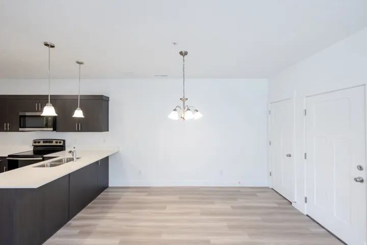 Kitchen featuring dark wood-finish cabinetry, stainless steel microwave, black electric range, and light-toned countertops