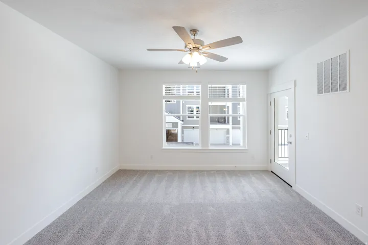 Recessed lighting, ceiling fan with light, large window with blinds, private balcony access, neutral carpeting
