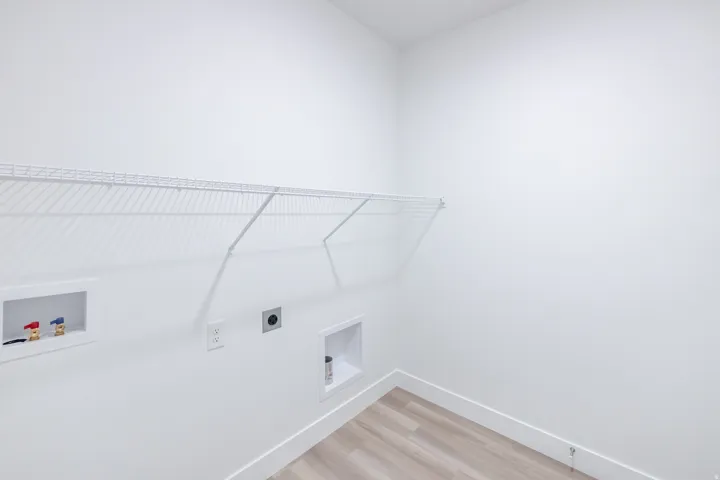 Utility room with wood-finish flooring, white walls, and a white wire shelf