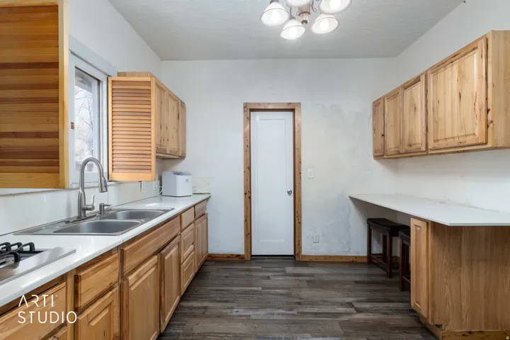 Kitchen featuring light countertops, dark wood finished floors, a kitchen breakfast bar, and a textured ceiling