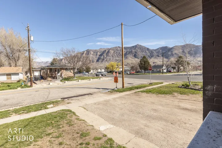 View of asphalt road featuring a residential view, sidewalks, traffic signs, and a mountain view