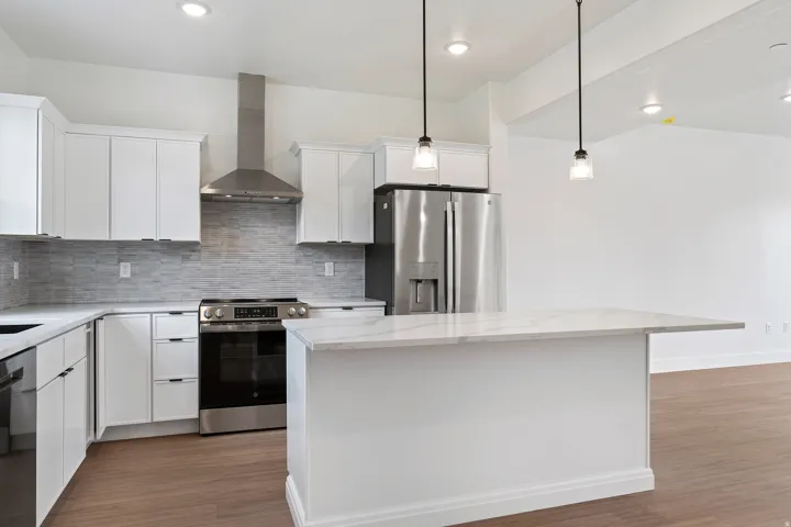 Kitchen with stainless steel appliances, white cabinets, a center island, and dark wood finished floors