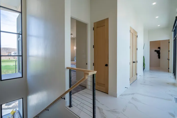 Hallway featuring an upstairs landing, recessed lighting, and light marble finish flooring