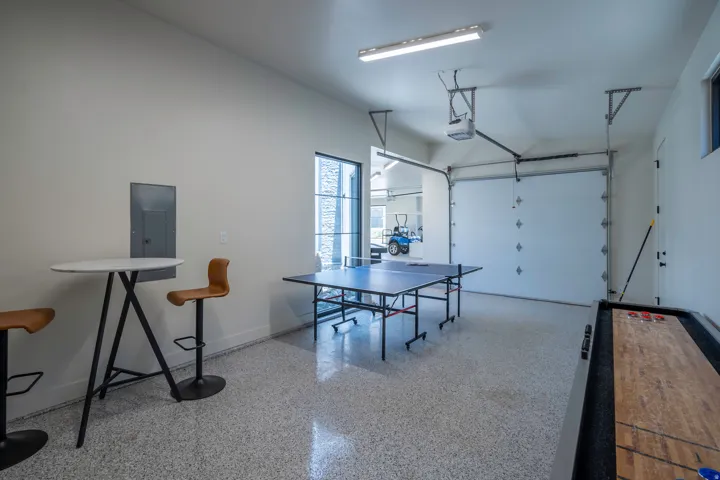 Game room with dark speckled floor, a garage, and electric panel