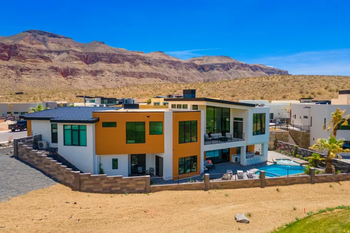 Back of house with a patio area, stucco siding, a fenced backyard, a mountain view, and a standing seam roof