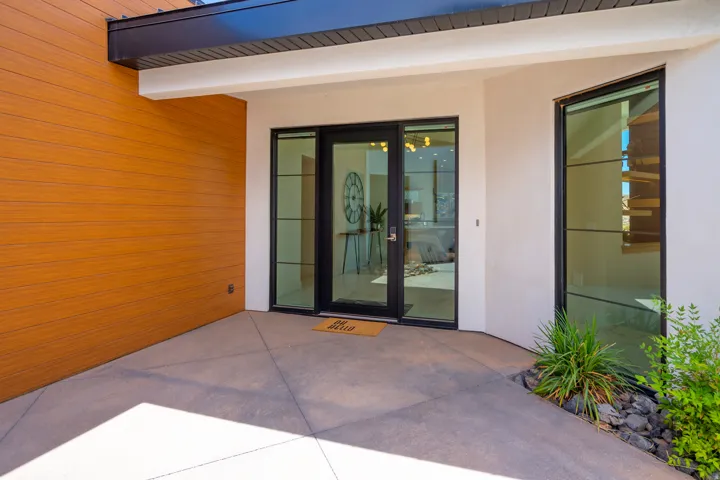 View of exterior entry featuring stucco siding and a patio